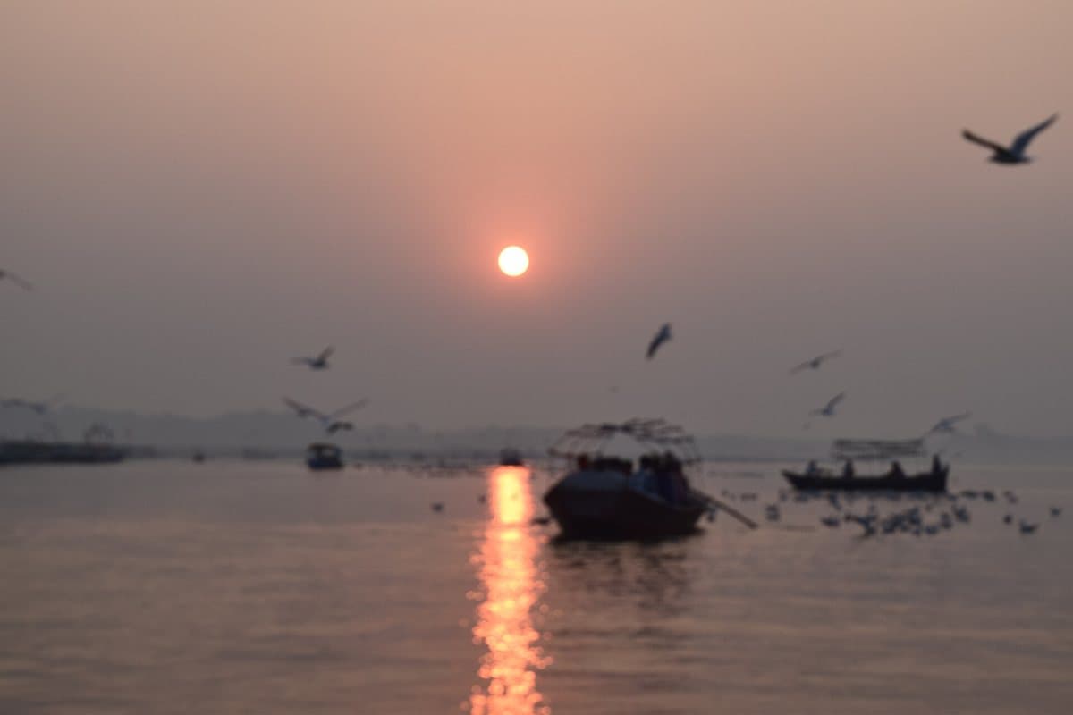 The sun rising over boats at the Sangam in Prayagraj