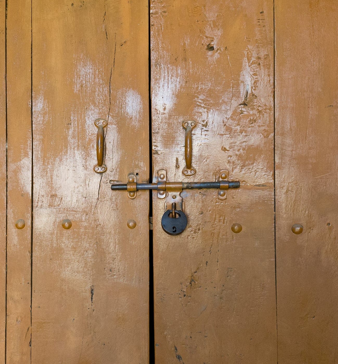 An old iron hasp and padlock on a wooden door in Punjab