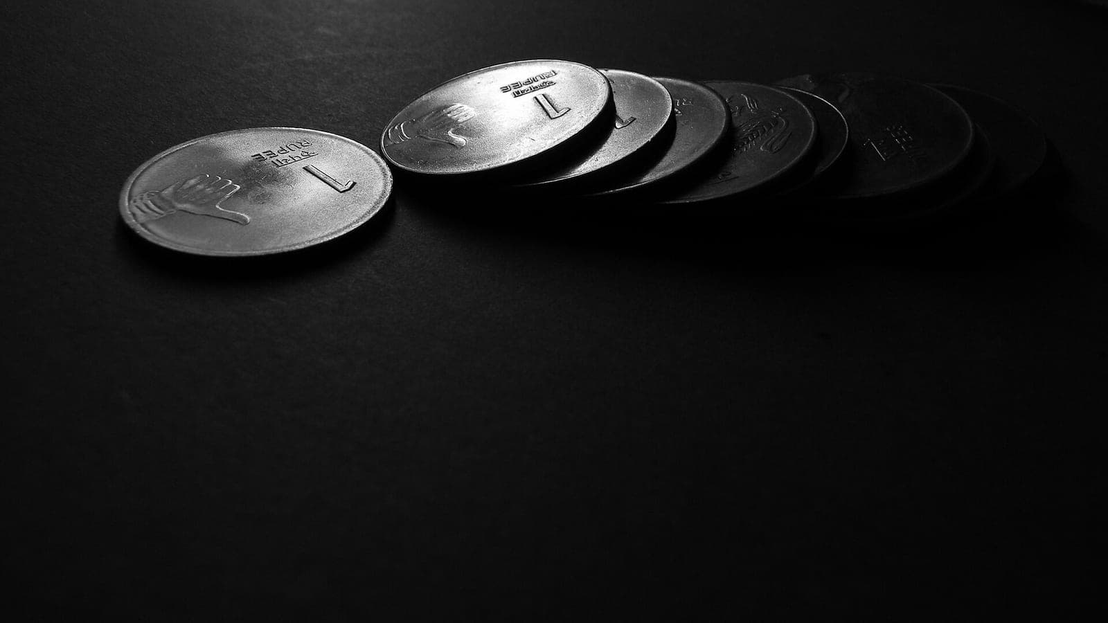 One-rupee coins in a row on a dark table