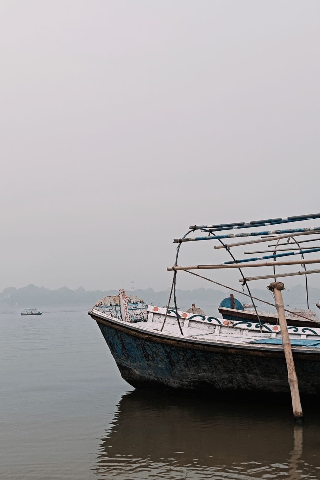 A wooden boat in the morning mist at the Triveni Sangam